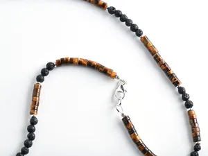 Makroaufnahme von Tigerauge- und Lavasteinperlen an einer schlichten Halskette