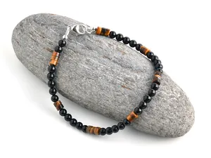 Detailaufnahme eines Tigerauge-Armbands mit schwarzen Perlen und silbernem Karabiner
