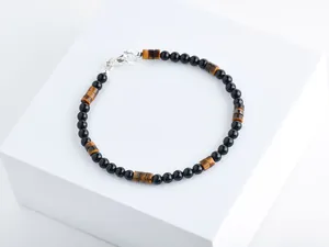 Detail von Perlenarmband mit schwarzen Onyx- und Tigeraugensteinen auf weißem Grund