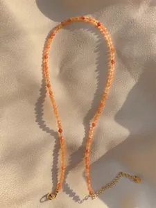 Macro detail of natural orange sunstone beaded necklace with 18k gold lobster clasp