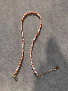 Detail of colorful stone beads necklace with gold lobster clasp and heart pendant