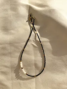 Detail of black spinel choker with freshwater pearls on a beige silk background