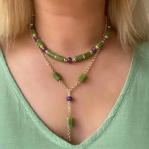 Zweilagige Perlenkette mit grünen Steinen und lila Kristallen auf goldener Kette