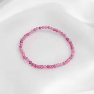 Détail des perles facettées en quartz fraise rose posées sur un tissu en soie élégant