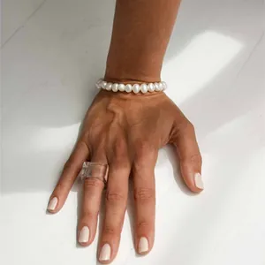 Elegante bracciale di perle d'acqua dolce naturali e anello in resina su sfondo minimal