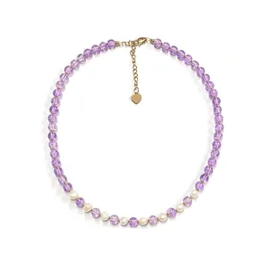 Purple cracked bead and freshwater pearl necklace with gold heart pendant on white background