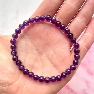 Close-up van een rekbare armband van paarse amethist kralen met glanzende afwerking