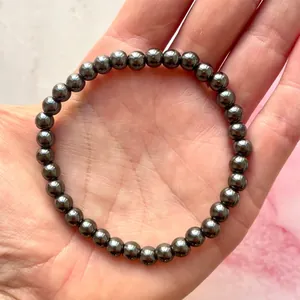 Detailopname van een donkergrijze hematiet kralenarmband op een handpalm