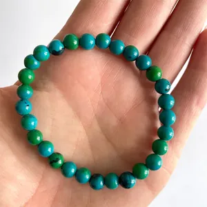 Macro-opname van een elastische armband met blauw-groene natuurstenen op een hand