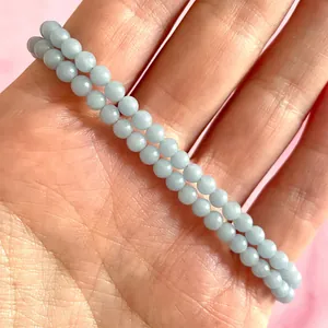 Detail van een licht blauwgroene natuurstenen dubbellaagse kralenarmband op de hand