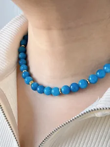 Nahaufnahme einer blauen Naturstein-Halskette mit 18k vergoldeten Elementen am Model