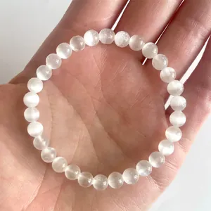 Macro-opname van een doorschijnende witte seleniet kralenarmband met kattenoogglans