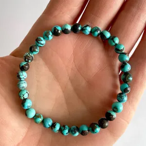Detailweergave van turquoise armband in de hand met natuurlijke zwarte adertextuur