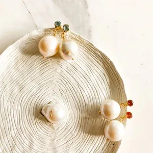 Orecchini vintage con perle barocche e pietre colorate su un vassoio ceramico