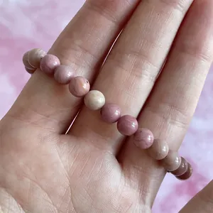 Detail van een roze natuurstenen kralenarmband met authentieke texturen om de pols