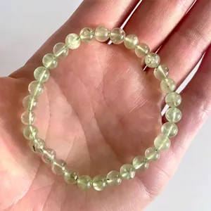 Detailopname van de elastische armband met lichtgroene natuurstenen kralen op een hand
