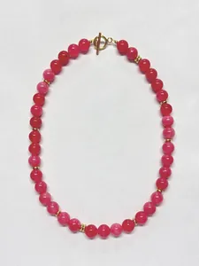 Nahaufnahme der magentafarbenen Perlenkette mit 18k Gold T-Bar Verschluss und Metallelementen