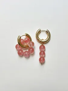 Dettaglio di orecchini a cerchio dorati con perline di pietra naturale rosa chic