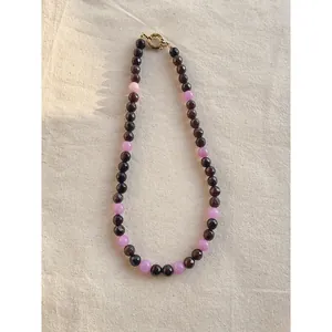 Collana con pietre naturali viola e chiusura dorata su sfondo in tessuto testurizzato