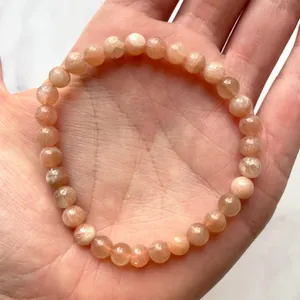 Macro-opname van gefacetteerde zonnesteen kralen armband op een elastisch koord in de hand