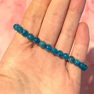Detail van blauwe natuurlijke edelsteen kralenarmband vastgehouden in hand met licht
