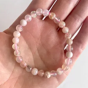Detail van 8mm kersenbloesem agaat kralen op een roze elastisch koordje