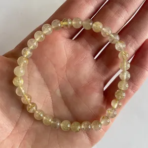 Macro-opname van gouden rutielkwarts kralenarmband met duidelijke naaldachtige insluitsels
