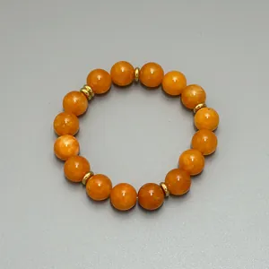 Detailaufnahme der orangefarbenen Natursteinperlen und goldenen Distanzstücke der Kette