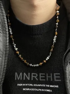 Detail van tijgeroog kralenketting met zilveren tussenstukken gedragen door een model