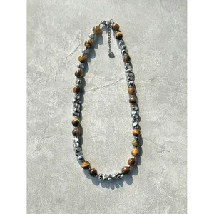 Tiger eye kralenketting met zilveren metalen accenten op stenen achtergrond