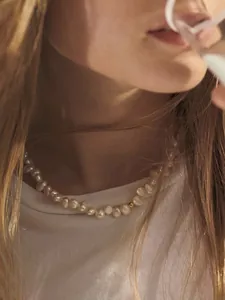 Gros plan d'un collier en perles d'eau douce baroques avec perle dorée porté par un mannequin