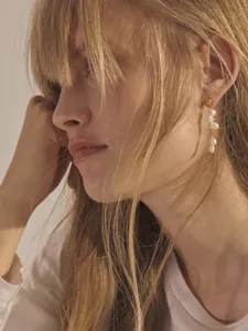 Gros plan détaillé de longues boucles d'oreilles en or avec quatre perles baroques
