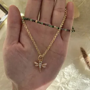 Collier avec pendentif libellé en or et perles de rubis et d'émeraude à la main