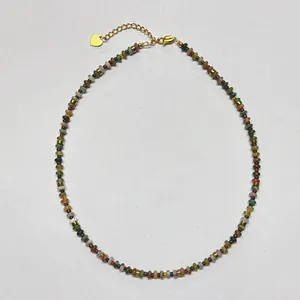 Detalle de collar bohemio de cuentas con colgante de corazón dorado y cierre de mosquetón