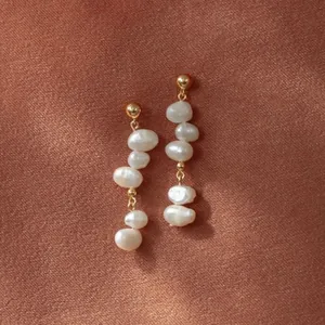 Boucles d'oreilles en perles baroques et clous dorés sur fond de soie texturée