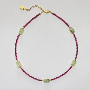 Macro detail of beaded necklace with red gemstones and golden heart tag extension