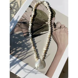 Bohemian style freshwater pearl necklace featuring a large iridescent shell pendant charm