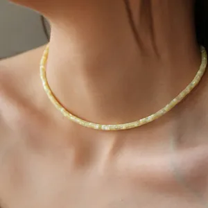 Collana girocollo minimalista in perline di conchiglia crema indossata da una modella