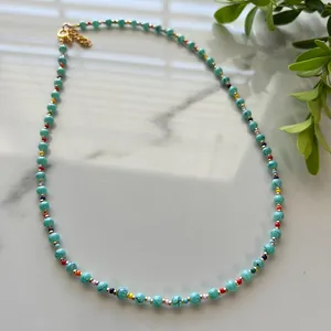 Detail of bohemian beaded necklace with turquoise stones and colorful beads on marble