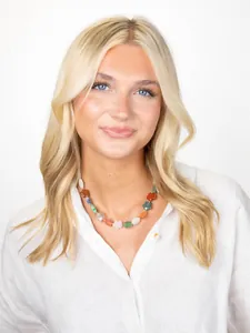 Detailopname van kleurrijke stenen kralenketting met bloemen bij een model in wit overhemd