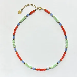Detail of handmade beaded necklace with colorful stones, gold heart charm, and lobster clasp