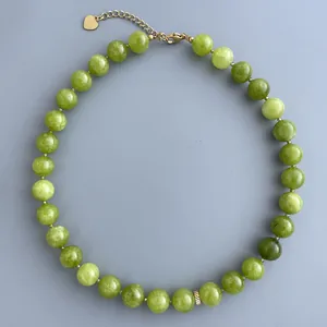 Dettaglio di perle in pietra naturale verde con chiusura dorata e ciondolo a cuore