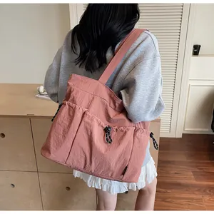Detail of pink nylon tote bag with multiple pockets and drawstring buckles for school