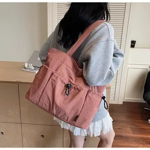 Detail view of large capacity multi-pocket tote bag in dusty rose nylon with side drawstring