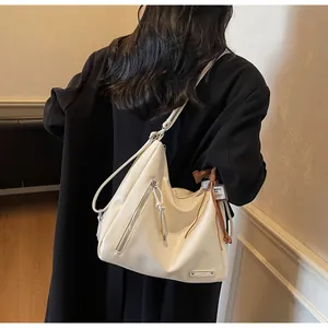 Détail du grand sac cabas crème avec fermeture éclair et breloque en cuir marron foncé