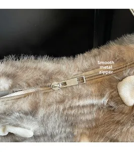 Gros plan du curseur de fermeture dorée sur le sac à dos en peluche marron doux