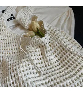 Close-up of white woven hollow tote bag with intricate crochet pattern and side drawstring
