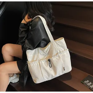 Detail of cream white tote bag featuring functional drawstring pockets and nylon texture