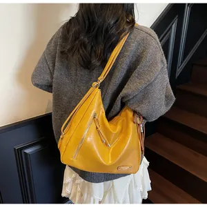 Gros plan sur un sac à bandoulière jaune vif avec texture en similicuir et détail de pompon