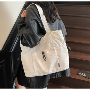 Detail of white nylon tote bag with drawstring pockets on a minimalist staircase